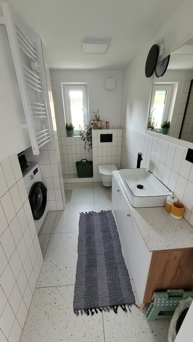 Nowoczesna łazienka w domku nad Sanem - wysoki standard wyposażenia, prysznic i pralka w obiekcie Cichosan. Nowoczesna łazienka w domku na wynajem Cichosan - wysoki standard wykończenia, duże lustro i elegancki design na Podkarpaciu.